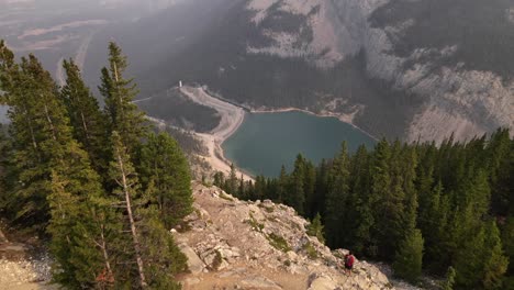 aerial drone video of a man with red t-shirt and a bag hiking and trekking through rocky mountains during wildfires