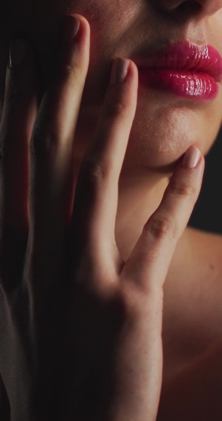 Close-up of Woman Touching Her Face with Glossy Pink Lips