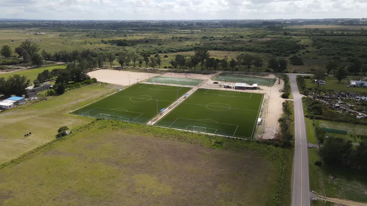 Shadows move across soccer fields in a rural landscape, revealing their vibrant green in this aerial view