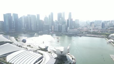 aerial-drone-shot-floating-over-marina-bay-sands-district-In-ultramodern-cityscape-of-Singapore,-along-the-Marina-Bay