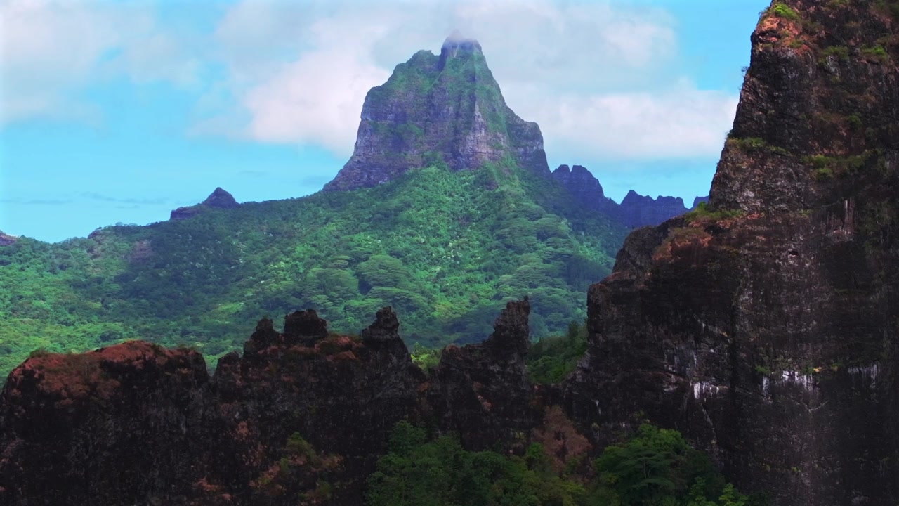 Moorea's dramatiska vulkaniska höga taggiga toppar oländig terräng Mount Rotui Mt Toheia Franska Polynesien flygdrönare Belvedere Lookout Cooks Opunohu Bay solig morgon blå himmel moln cirkel höger parallax