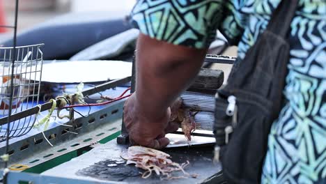 el vendedor prepara y asada calamares en la calle