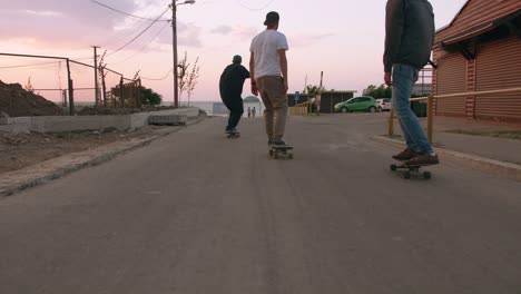 group of young people skateboarding on the road in the early morning near the sea, close up shot