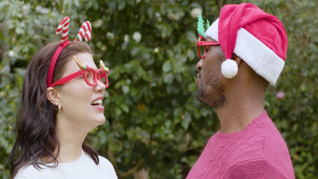 At Christmas, Couple enjoying holiday spirit, adjusting festive glasses outdoors, smiling together