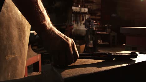 Mid-section-of-blacksmith-holding-pliers