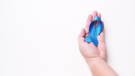 detail of male hand holding ribbon in light blue color on white background