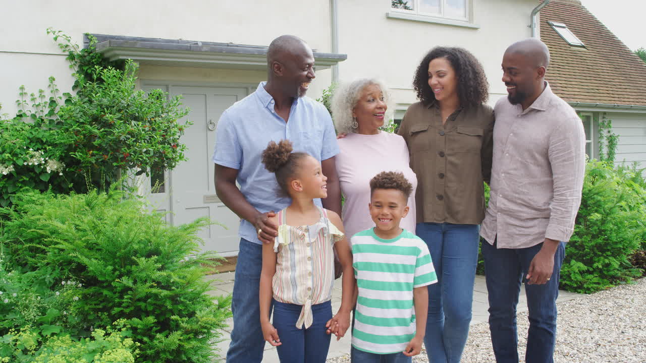 retrato de una familia de varias generaciones sonrientes de pie fuera de casa juntos