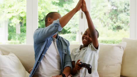 father and son giving high five to each other while playing video game