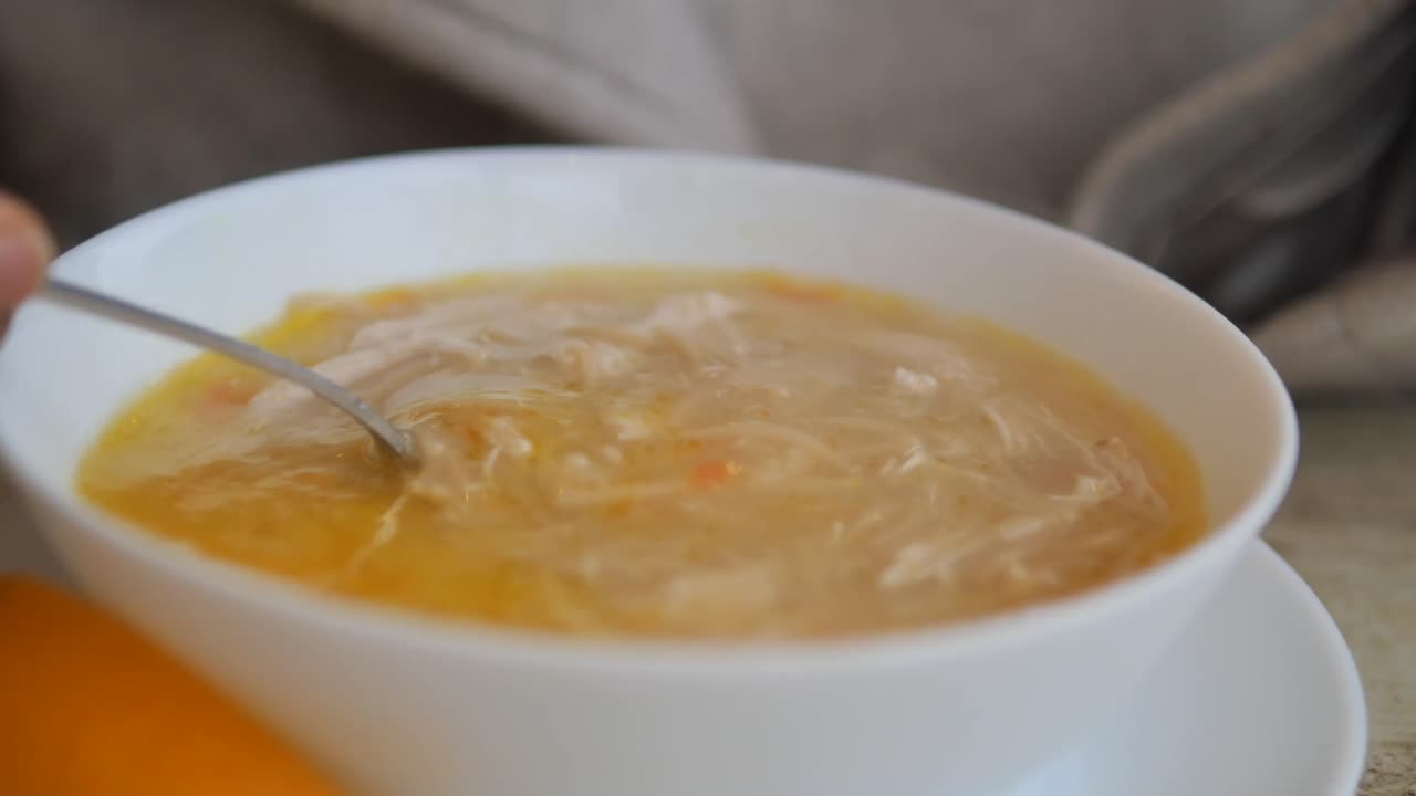 Nærbillede af en ske, der rører rundt i varm kyllingnudelsuppe