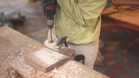 carpenter working drilling a hole with woodworking machines in carpentry shop