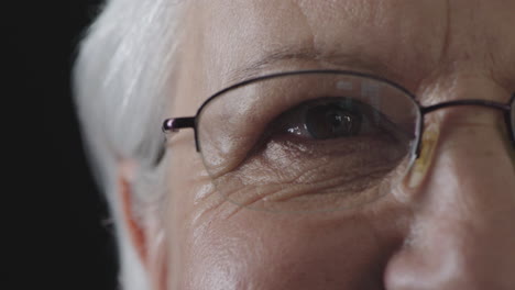 cerca del ojo de una mujer mayor mirando a la cámara parpadeando con gafas