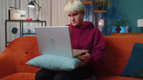 young woman freelancer starts working on laptop pc, sends messages, makes online purchases at home