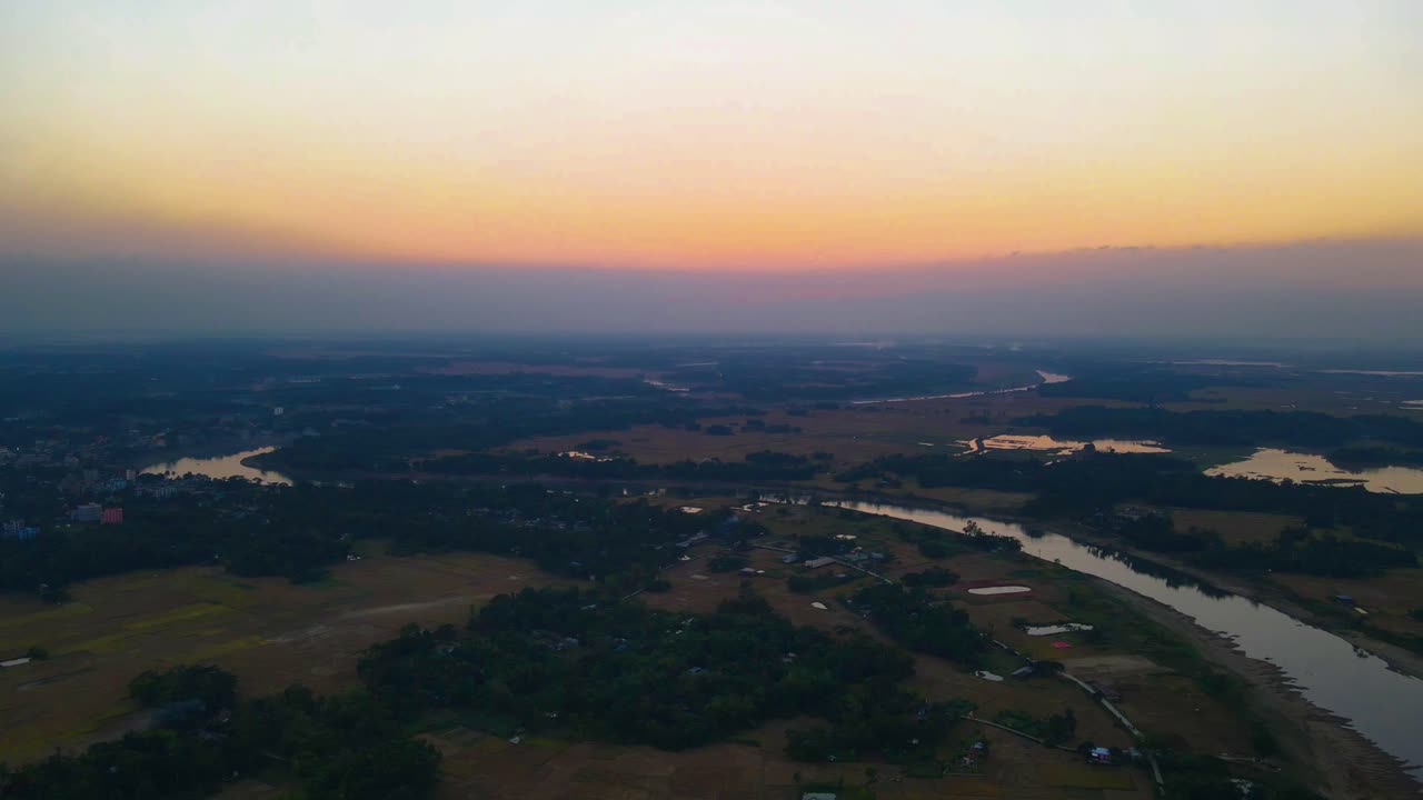 hermosa puesta de sol sobre tierras de cultivo en bangladesh con el río surma en primer plano