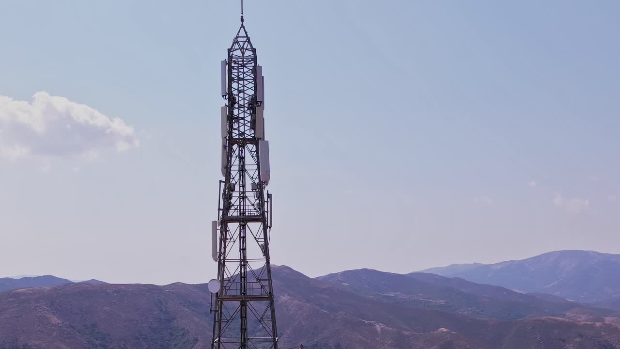 Vista rotante di una torre di telecomunicazioni con montagne e cielo