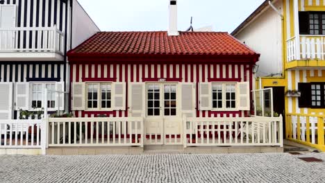 Charming-and-colorful-house-with-red-stripes-and-a-white-fence-in-Costa-Nova-do-Prado,-Portugal