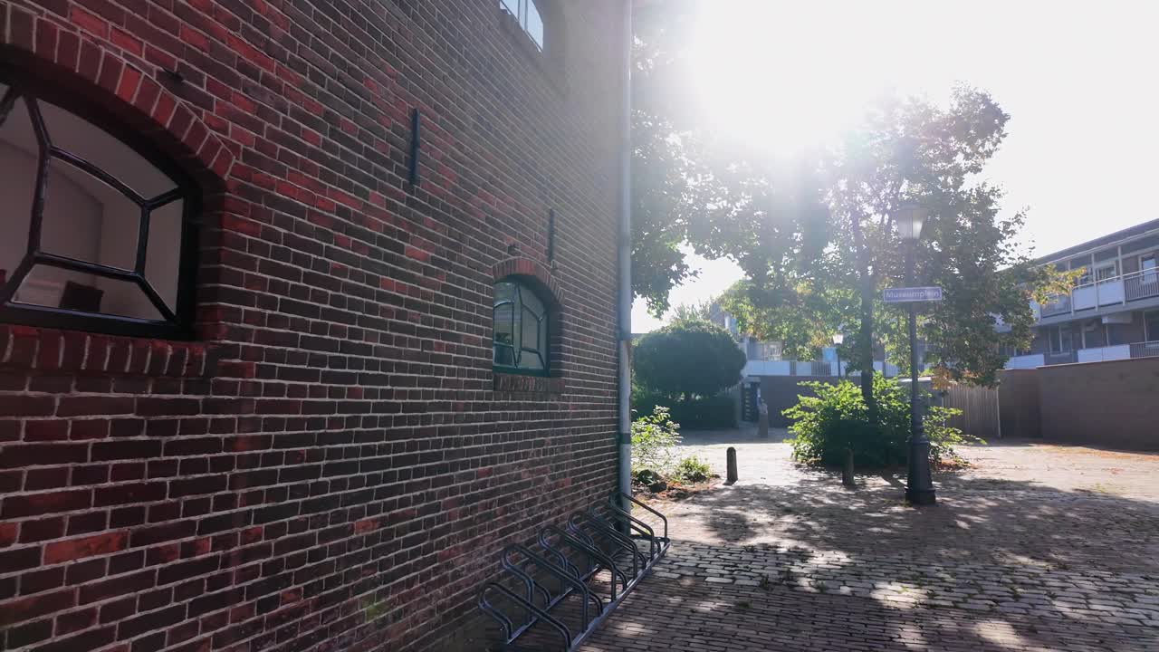 Close-up view of a red brick wall with arched windows and empty bicycle racks in Coevorden. Location: Coevorden, Drenthe, Netherlands – Coevorden, Drenthe, Nederland