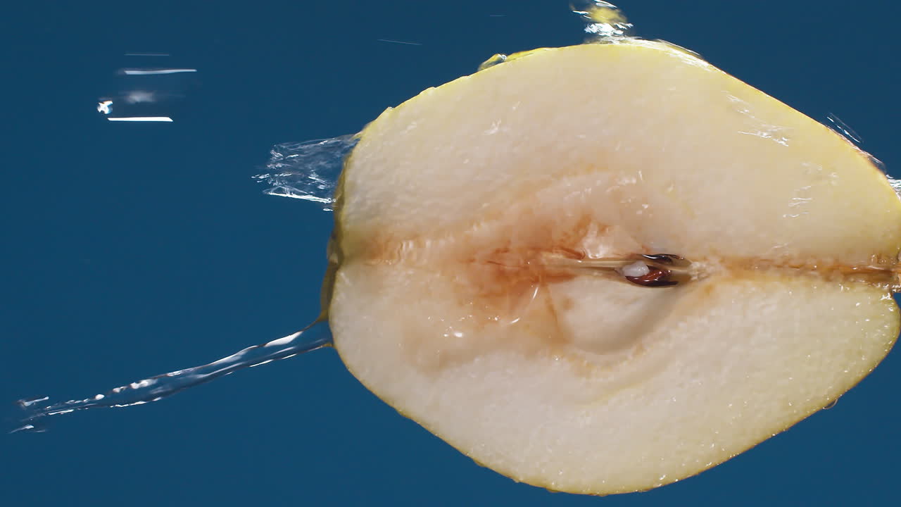Detail of pear slice with water falling on the piece in slow motion