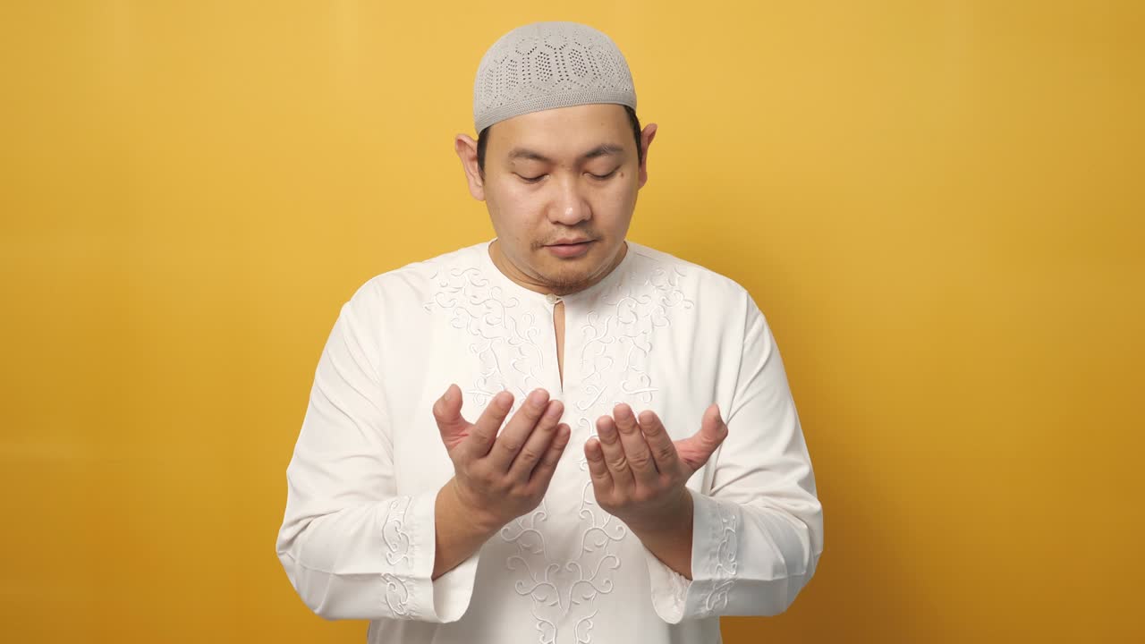 아시아 무슬림 남자의 초상화 하나님께 기도, 기도 몸짓 손을 올려, 노란색에 대항
