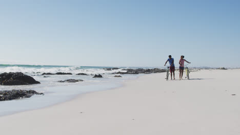 Afroamerikanisches-Paar-Spaziert-Mit-Fahrrädern-Am-Strand