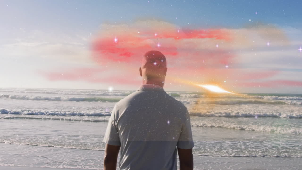 Man standing on beach with colorful cosmic animation in sky