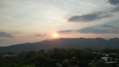 Drone-Shot-Rising-Over-Tree-in-Foreground-Revealing-Sunset-Over-Alajuela-Countryside