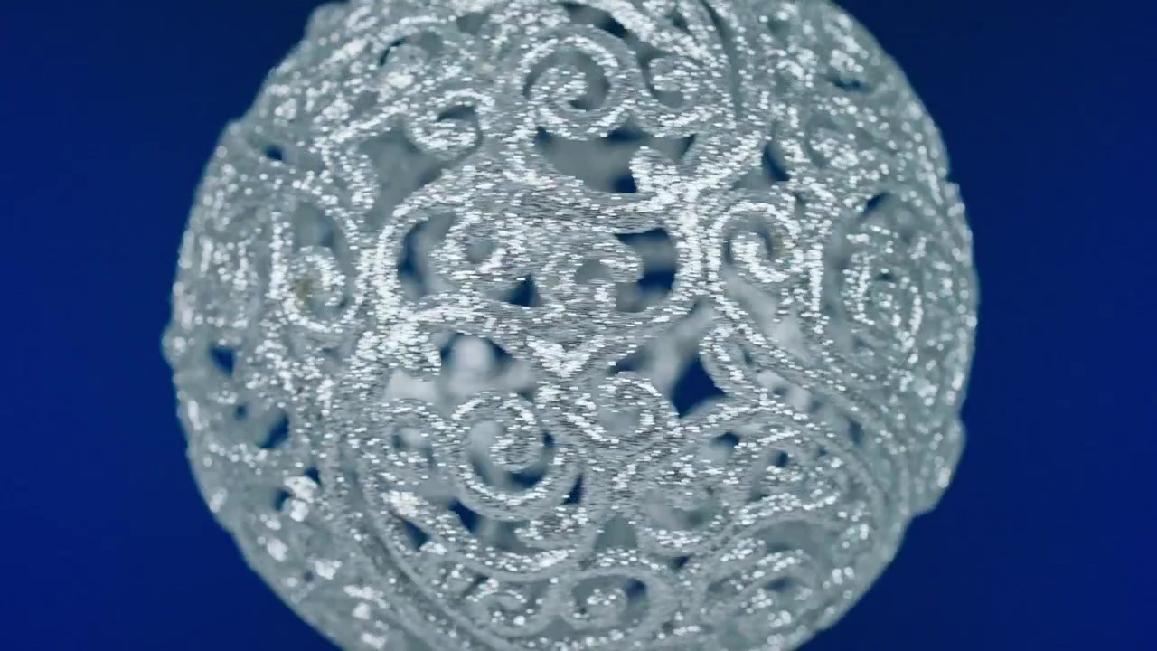 Decorazione natalizia glitterata argento che ruota su sfondo blu.