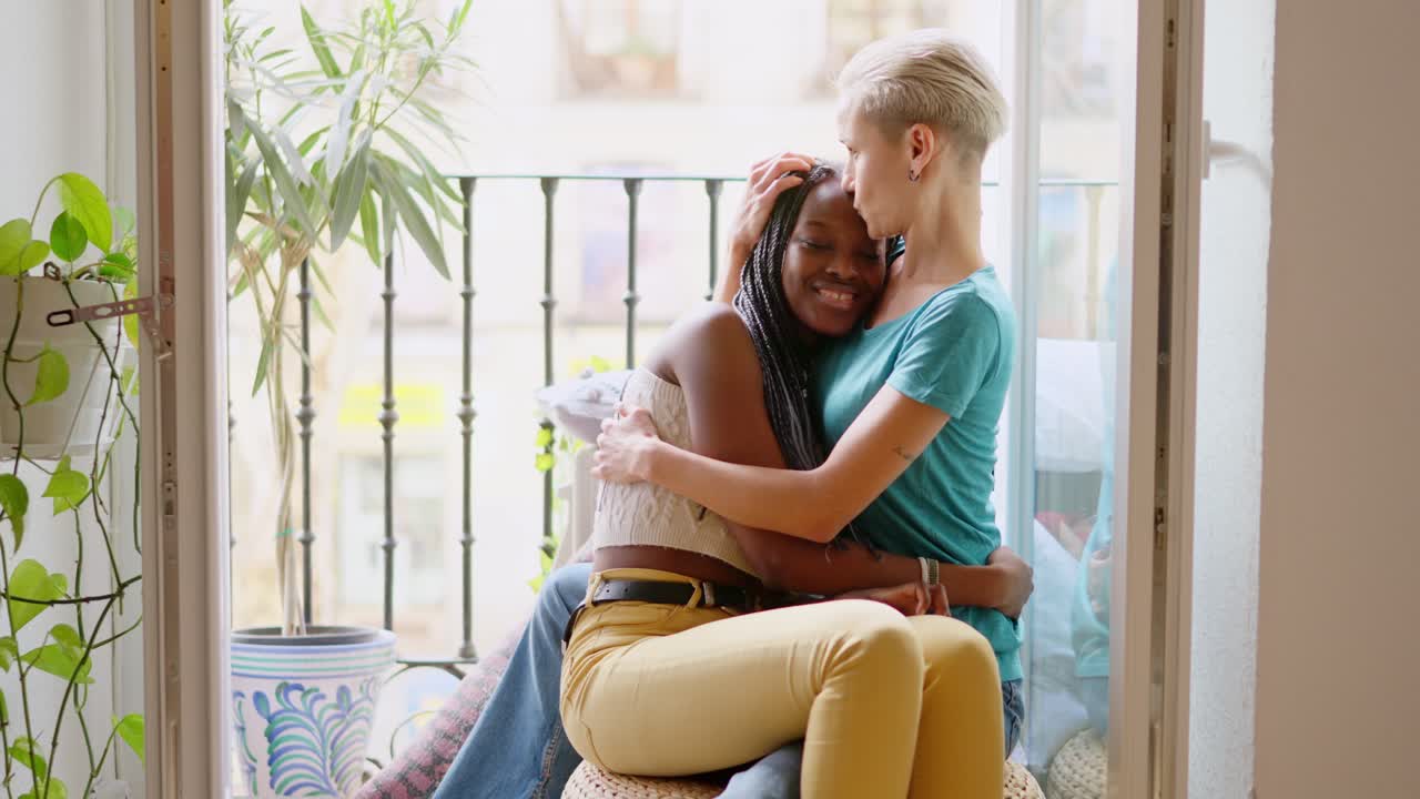 Two women sharing a loving embrace on a balcony