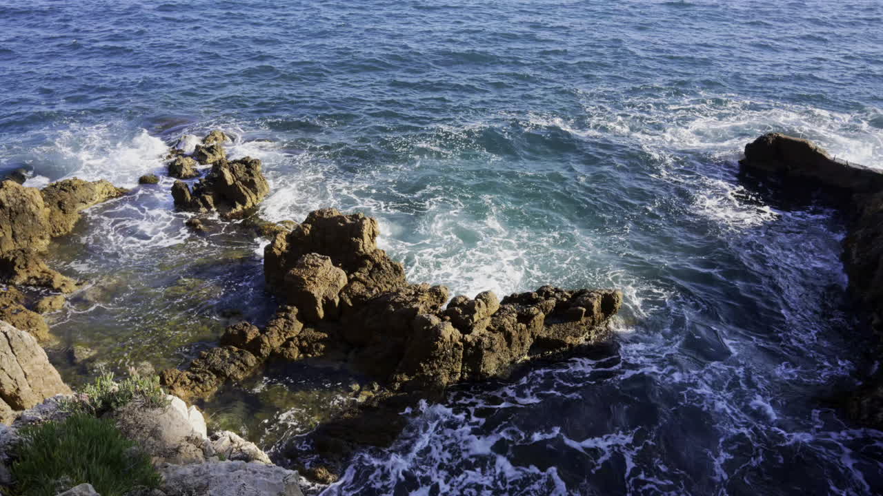 The waves of the Mediterranean Sea crashing on the rocks on the shore of the French Riviera
