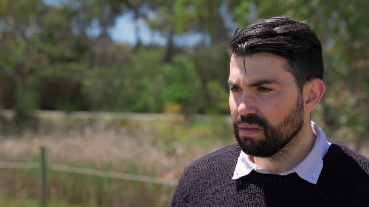 un hombre hablando con otra persona afuera bajo el sol durante el día