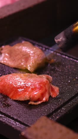 bistec siendo sazonado y cocinado en una placa caliente
