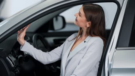 stylish girl sitting in the car evaluates the interior of the car inside