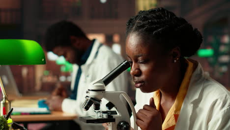 female science student examines cells under microscope for scientific research