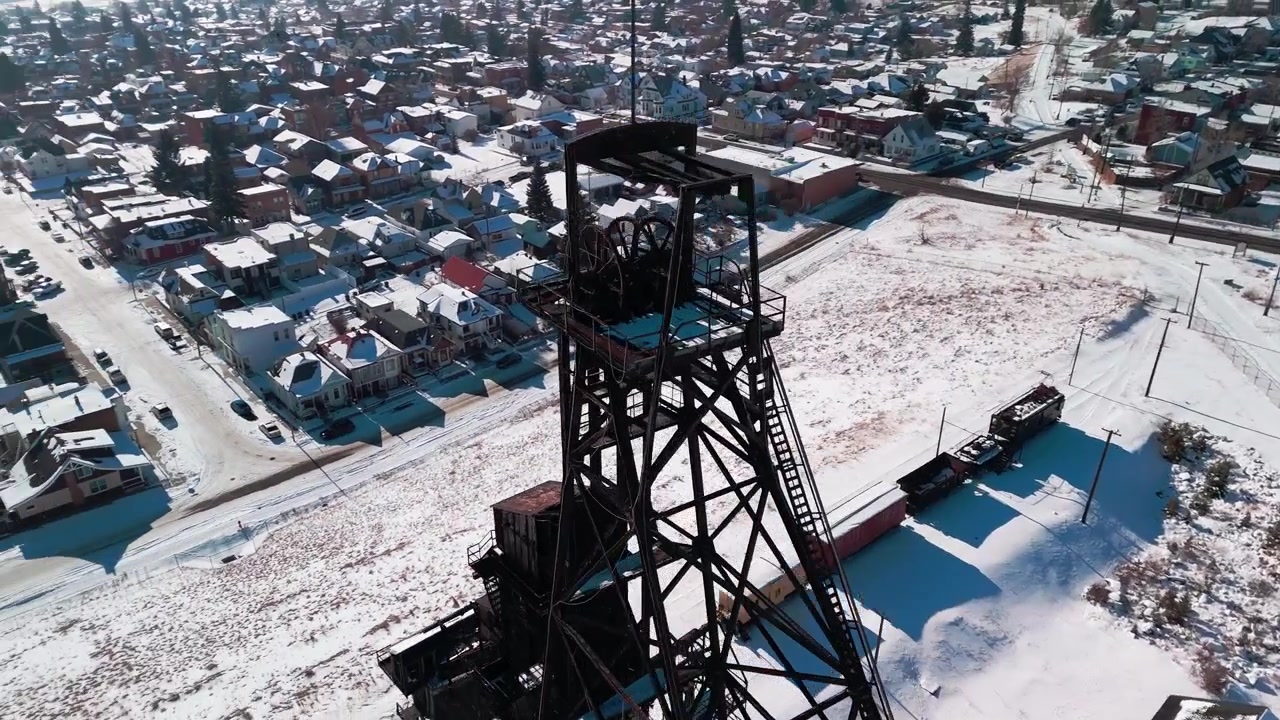 Low-altitude drone glide over Butte, Montana, highlighting historic industrial headframes and snow-covered terrain reflecting the region's prominent hard-rock mining heritage