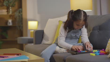 young girl on asd spectrum at home sitting on sofa solving shape puzzle 5