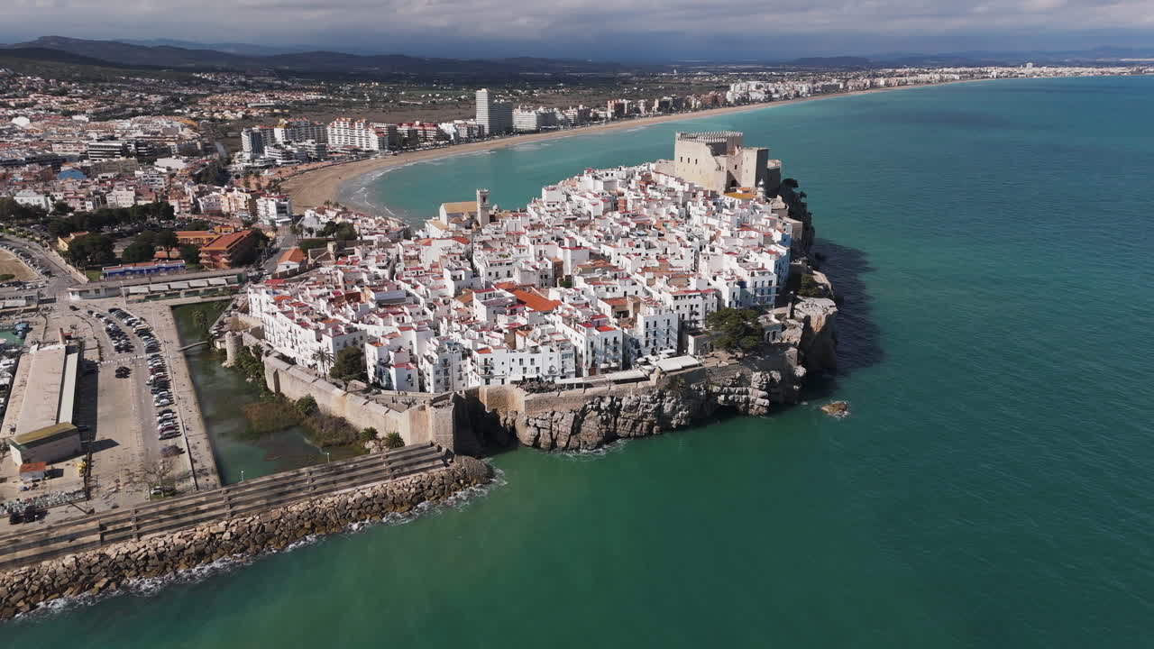 Sunny aerial of Peniscola’s castle and town jutting into sea with marina to one side