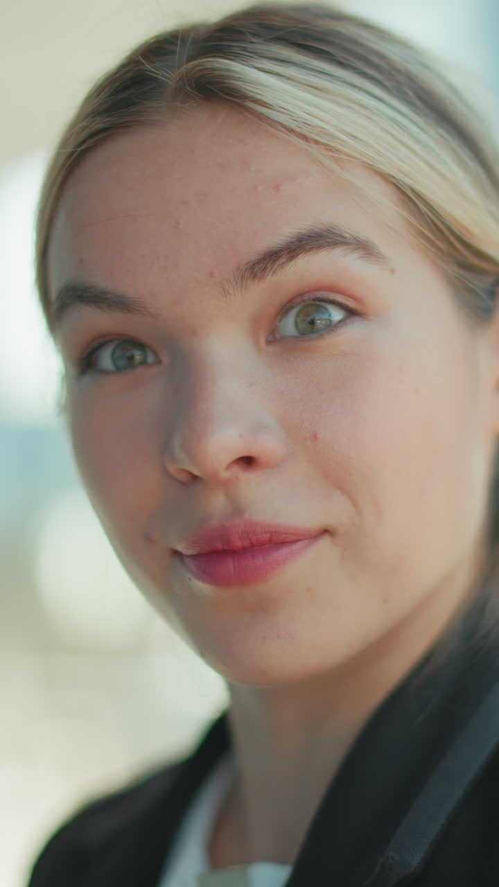 Close-up of elegant lady with cat eyes, smiling and staring at the camera, wearing suit in professional attire, with blurred urban background