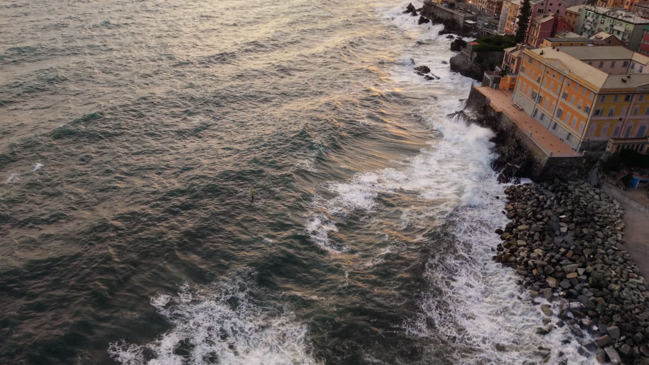 Drone aereo che sorvola le potenti onde lungo la costa rocciosa di Genova, Liguria, Italia