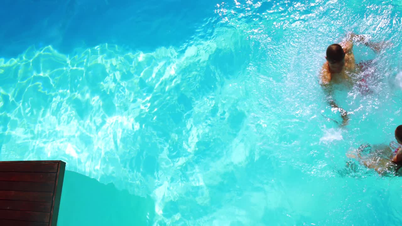 Pasangan bahagia melompat ke kolam renang biru jernih