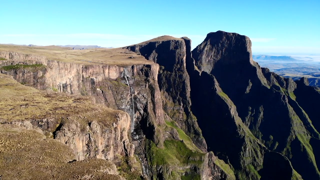 Altopiano soleggiato aereo che si affaccia su una gola in ombra, ampio panorama diurno di ripide scogliere di basalto e profonda. Media