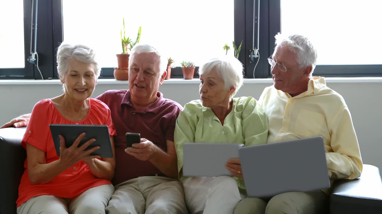 Anziani che usano tablet digitale, telefono cellulare e laptop