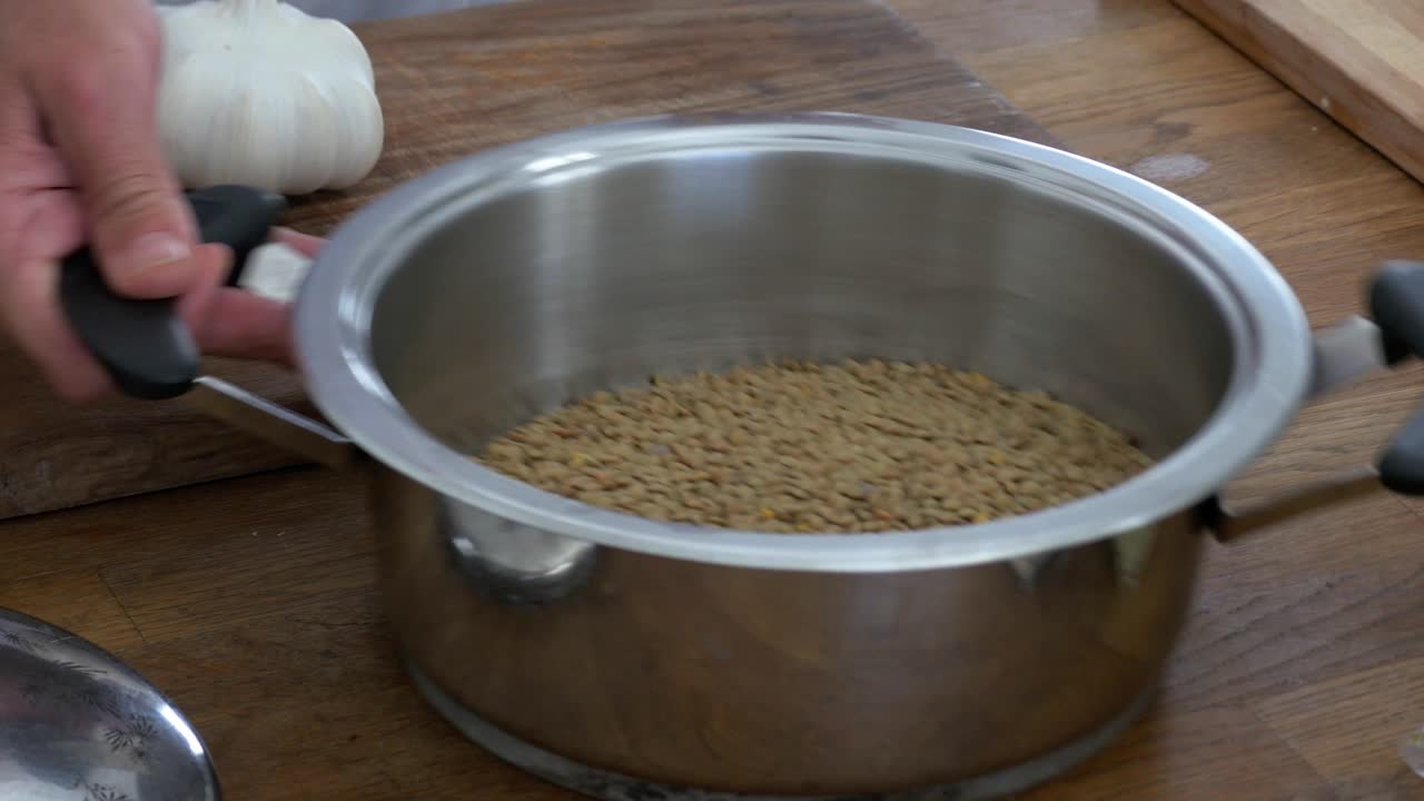 Pouring lentils into a stainless pot and shaking before soaking