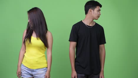 young asian couple letting go and looking away together