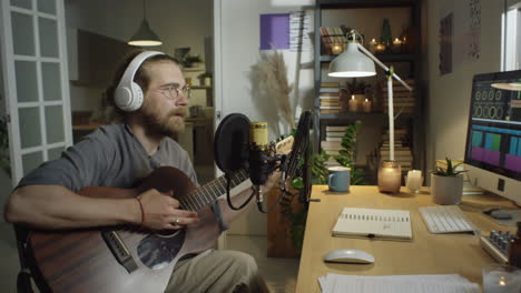 man playing guitar and singing in home music studio