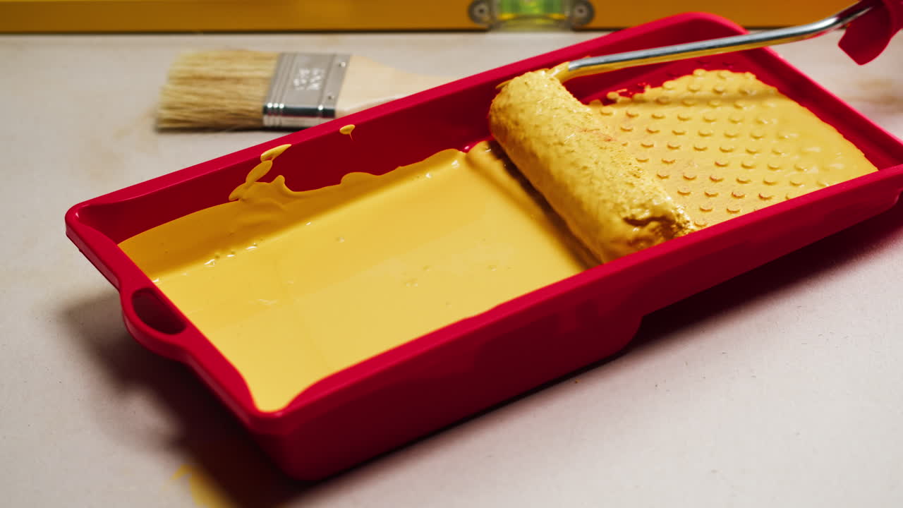 Rullo intinto in vernice gialla in un vassoio rosso