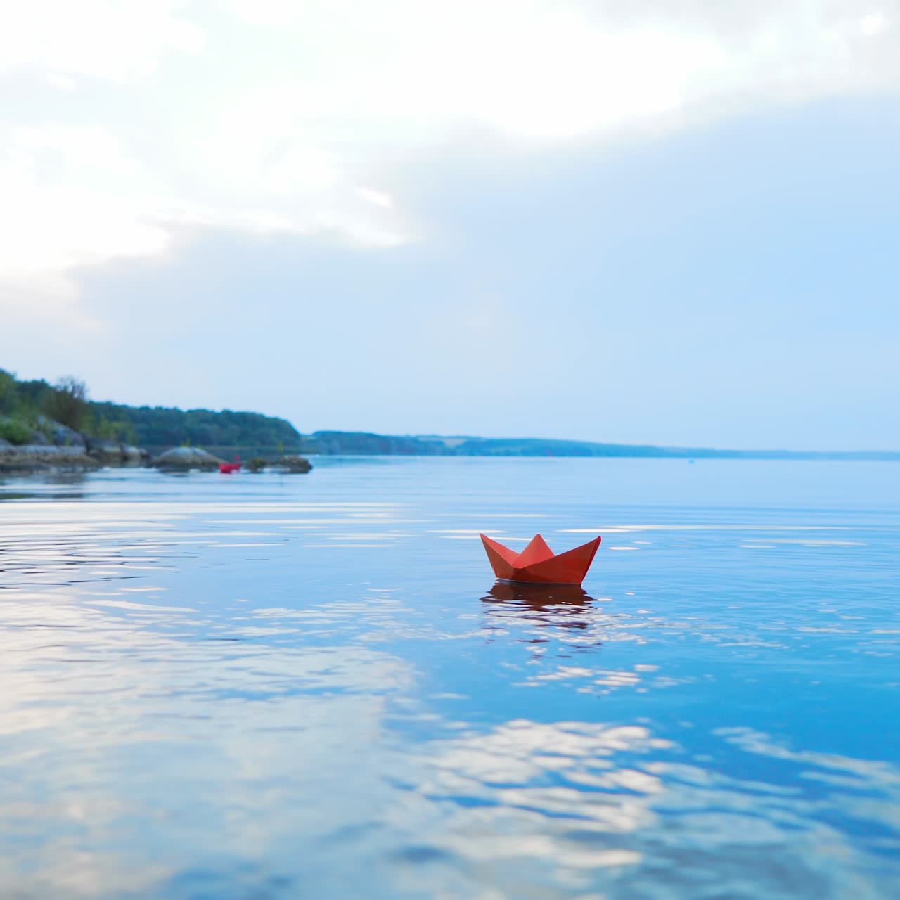 A paper boat floating away into the distance. Boat on the water. Beautiful sunset. Origami. River. Lake.