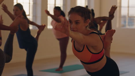 Junge,-Gesunde-Frau-Im-Yoga-Kurs,-Die-Die-„Lord-Of-The-Dance“-Pose-übt-Und-Bei-Sonnenaufgang-Mit-Einer-Gemischtrassigen-Gruppe-Von-Menschen-Im-Fitnessstudio-Trainiert