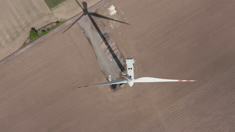 aerial reveal of a huge wind turbine generating renewable energy in the farm on a sunny day