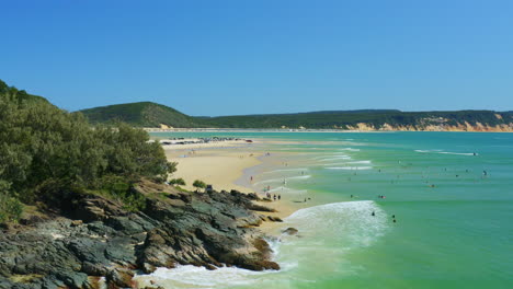 Aerial-4K-Drone-Over-Tourists-Swimming-Off-Sandy-Beach-Shore-With-Cars-Camping-On-Sand,-Australia