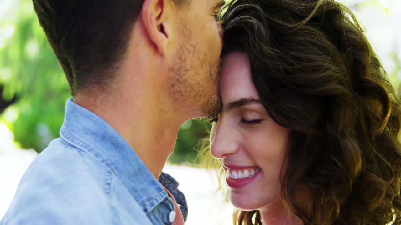 Affectionate man kissing woman in park