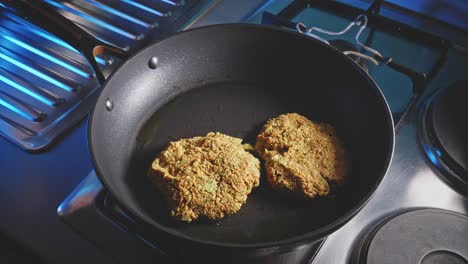 man putting prepared veggie patties on a hot non-stick frying pan, close-up shot